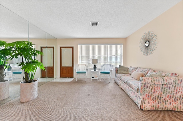 carpeted living room featuring visible vents and a textured ceiling