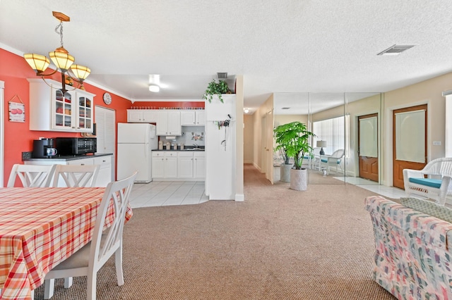 kitchen featuring visible vents, glass insert cabinets, freestanding refrigerator, light carpet, and black microwave