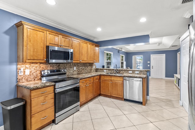 kitchen featuring a peninsula, decorative backsplash, stainless steel appliances, and a sink