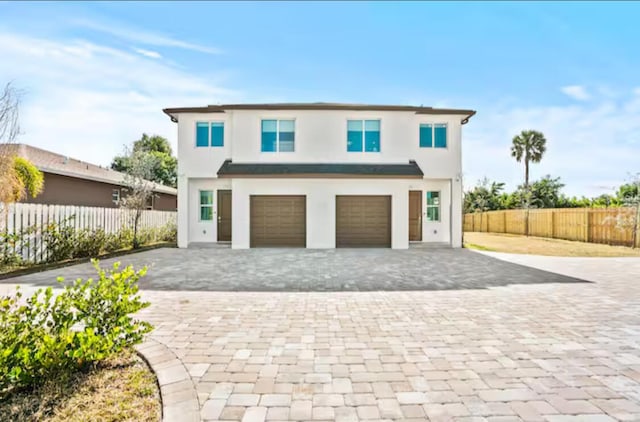 view of front of home featuring decorative driveway, fence, an attached garage, and stucco siding