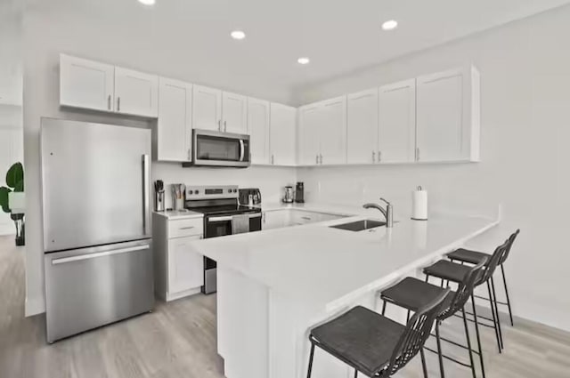 kitchen with light countertops, appliances with stainless steel finishes, a sink, and white cabinetry