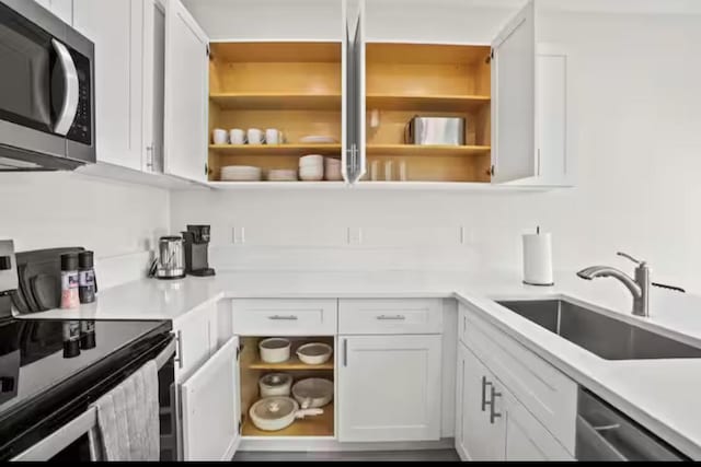 kitchen featuring open shelves, light countertops, appliances with stainless steel finishes, white cabinets, and a sink