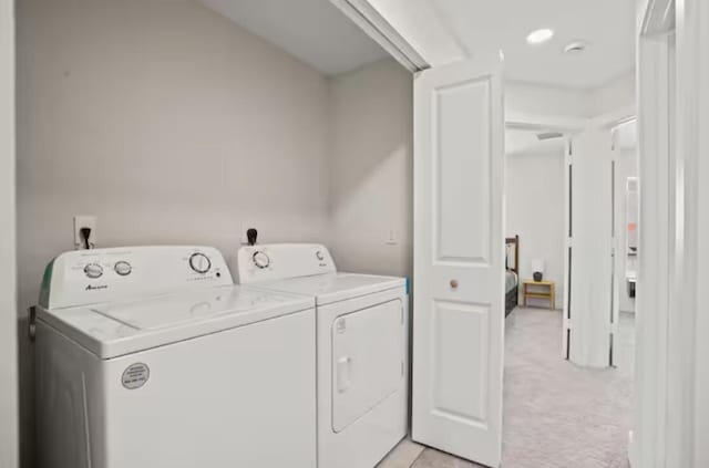 clothes washing area with laundry area, light carpet, and washing machine and clothes dryer