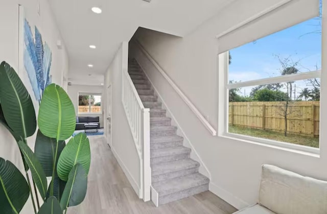 staircase with baseboards, wood finished floors, and recessed lighting