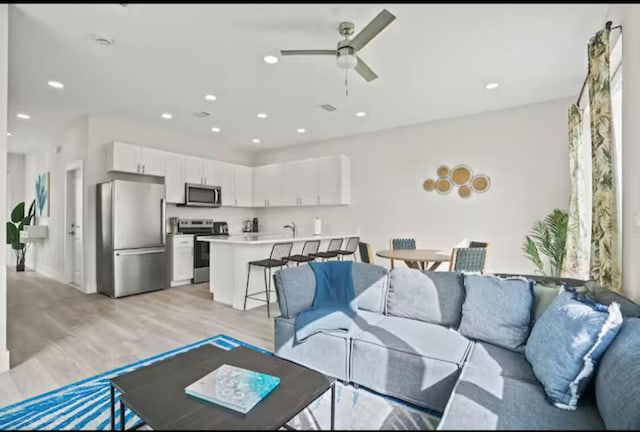 living room with a ceiling fan, light wood-style flooring, and recessed lighting