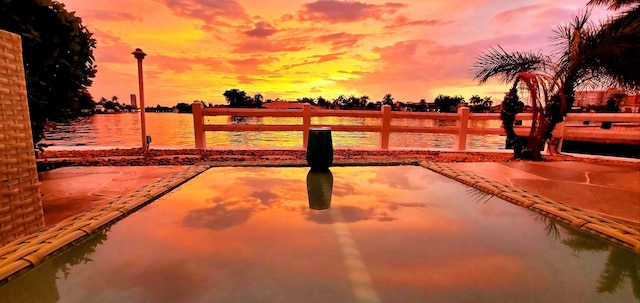 patio terrace at dusk featuring a water view