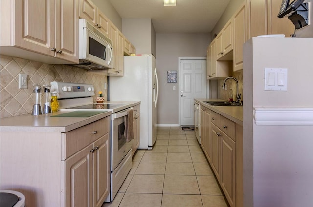 kitchen with white appliances, tasteful backsplash, light tile patterned floors, light countertops, and a sink