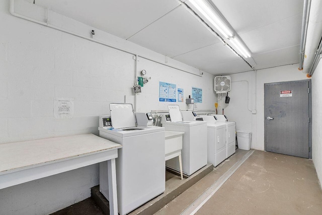 common laundry area with separate washer and dryer and concrete block wall