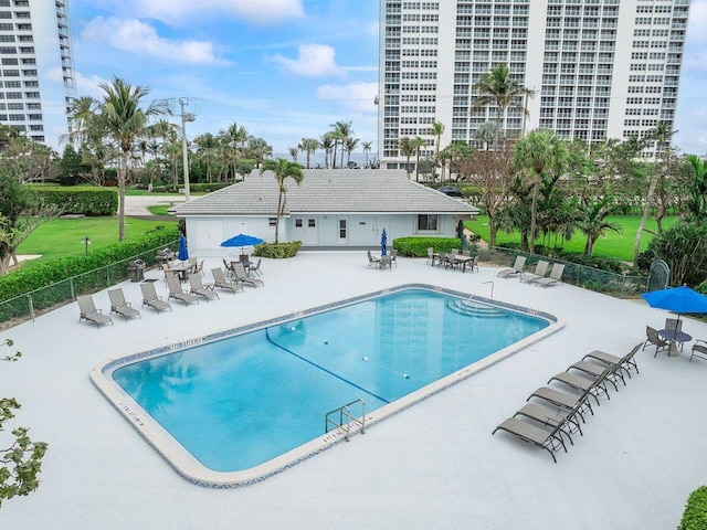 community pool with a patio area and fence