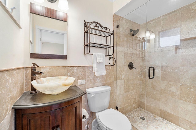 full bath with wainscoting, tile walls, a shower stall, and vanity