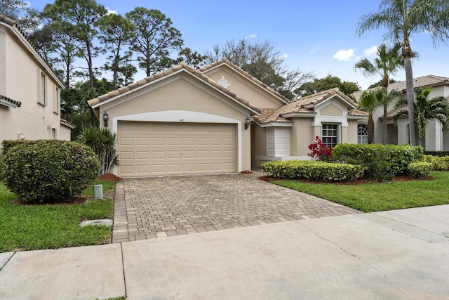 mediterranean / spanish-style house with a garage, a tiled roof, decorative driveway, and stucco siding