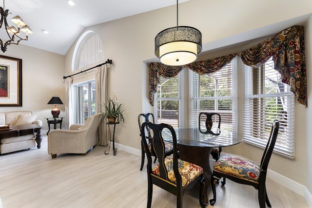 dining room with high vaulted ceiling, light wood-type flooring, and baseboards