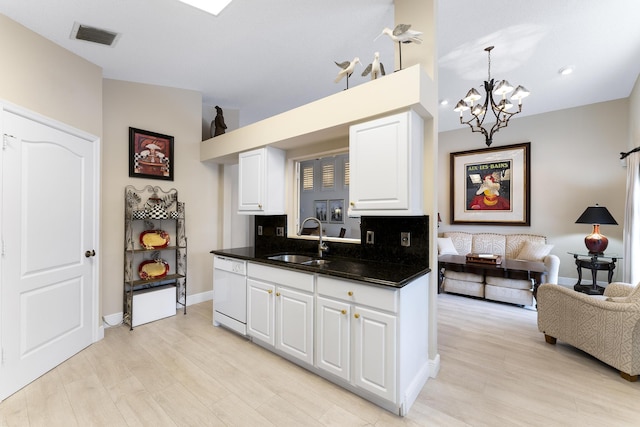 kitchen featuring dark countertops, visible vents, white cabinetry, white dishwasher, and a sink