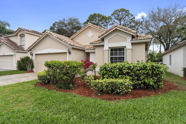 mediterranean / spanish-style house featuring a garage, a tiled roof, decorative driveway, a front yard, and stucco siding