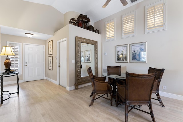 dining room with visible vents, baseboards, a ceiling fan, light wood-style flooring, and high vaulted ceiling