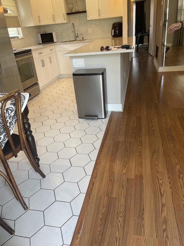 kitchen with white cabinets, electric range, light countertops, and a sink