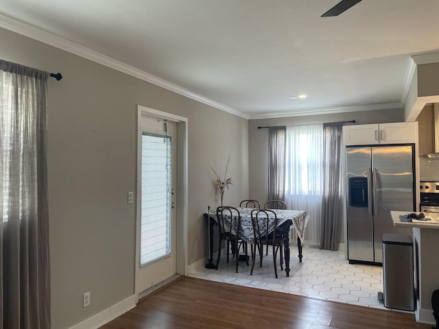 dining room with light wood-style floors, ornamental molding, and baseboards