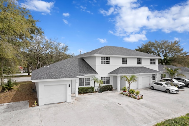 traditional-style house featuring a shingled roof, concrete driveway, and stucco siding