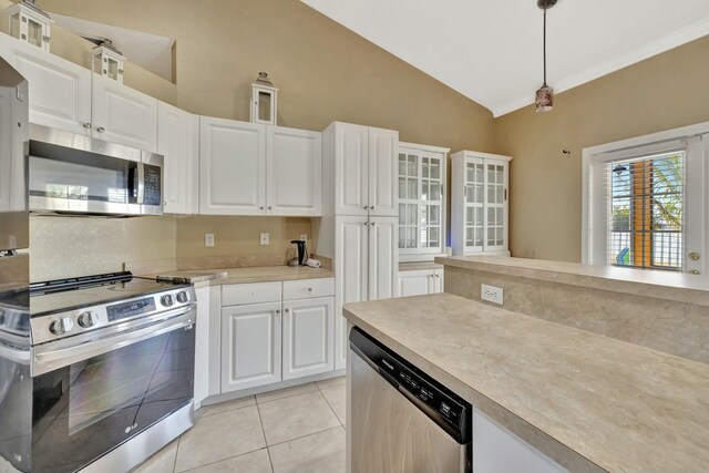 961 SW Haas Ave, Port Saint Lucie, FL 34953 - kitchen featuring appliances with stainless steel finishes, vaulted ceiling, light countertops, light tile patterned flooring, and white cabinetry