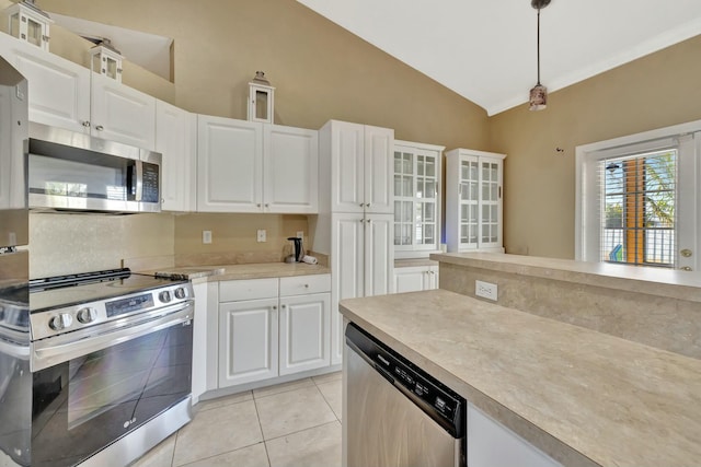 961 SW Haas Ave, Port Saint Lucie, FL 34953 - kitchen with stainless steel appliances, light tile patterned floors, white cabinetry, vaulted ceiling, and light countertops