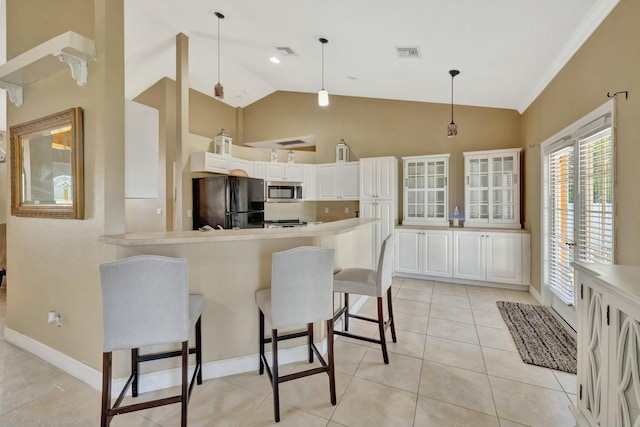 961 SW Haas Ave, Port Saint Lucie, FL 34953 - kitchen featuring stainless steel microwave, a breakfast bar, freestanding refrigerator, visible vents, and a peninsula