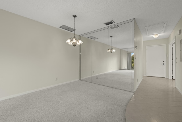 empty room featuring a textured ceiling, carpet flooring, visible vents, and baseboards