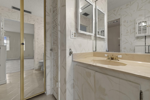 bathroom featuring tile patterned flooring, visible vents, a textured ceiling, and wallpapered walls