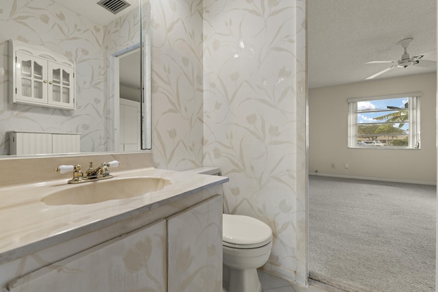 bathroom with wallpapered walls, visible vents, toilet, a textured ceiling, and vanity