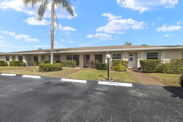 single story home with uncovered parking, a front yard, and stucco siding