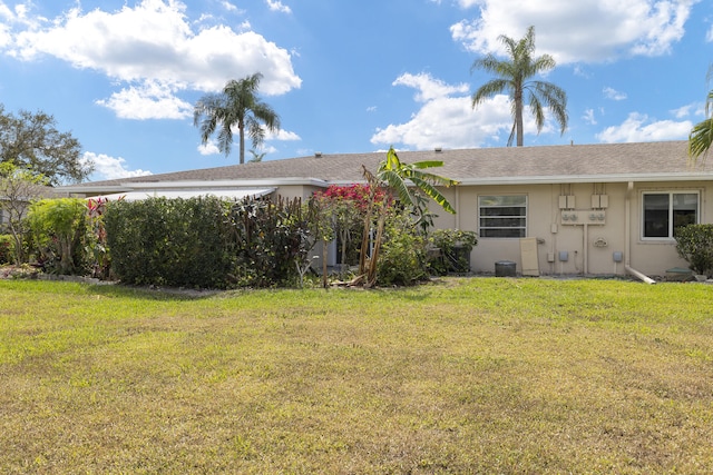 back of house with a yard and stucco siding