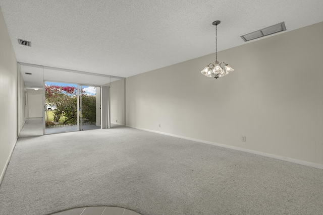 carpeted spare room with visible vents, a textured ceiling, and baseboards