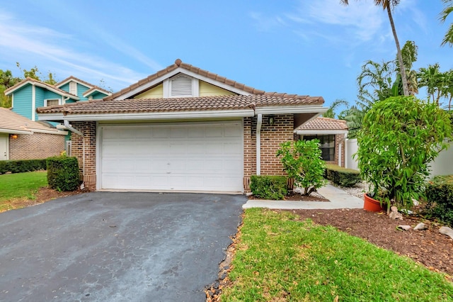 view of front of house featuring brick siding, driveway, a tiled roof, and an attached garage