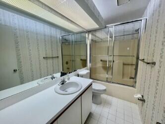 full bathroom featuring wallpapered walls, toilet, tile patterned flooring, combined bath / shower with glass door, and vanity