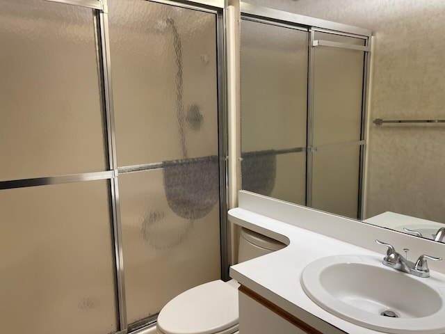 bathroom with a shower stall, toilet, and vanity