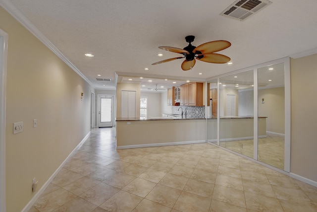 interior space with tasteful backsplash, visible vents, baseboards, glass insert cabinets, and ornamental molding