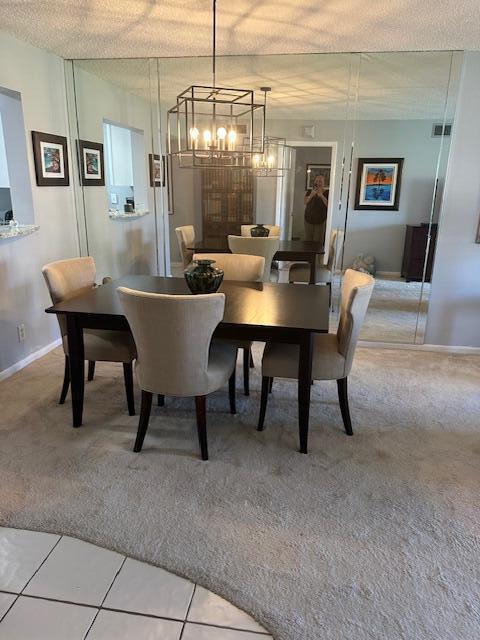 tiled dining space featuring visible vents, a textured ceiling, baseboards, and carpet flooring