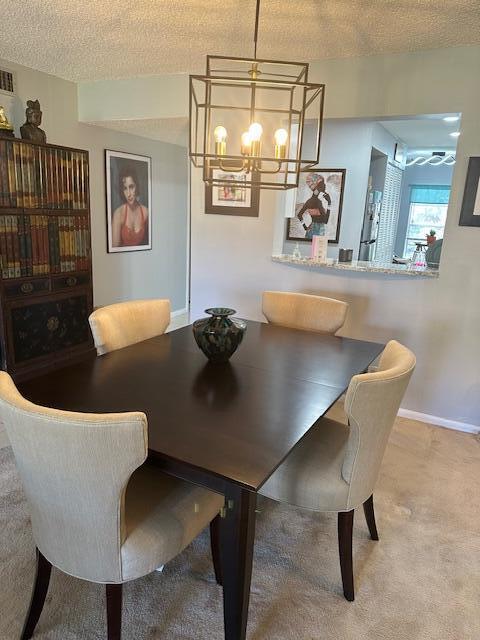 carpeted dining space with visible vents, a notable chandelier, a textured ceiling, and baseboards