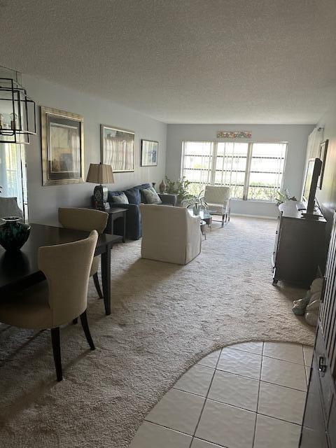 living area with light tile patterned floors, a textured ceiling, and light colored carpet