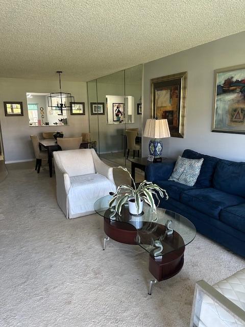 carpeted living area with a notable chandelier and a textured ceiling