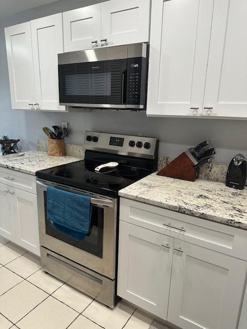 kitchen featuring light tile patterned floors, stainless steel appliances, white cabinetry, and light stone countertops