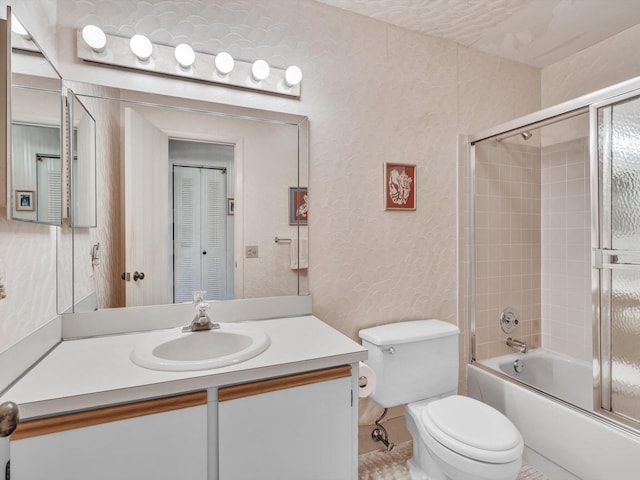 bathroom with enclosed tub / shower combo, vanity, toilet, and wallpapered walls