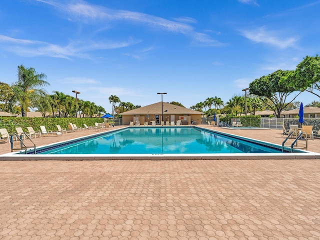 community pool with fence and a patio