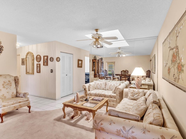 living area featuring a textured ceiling, ceiling fan, light tile patterned flooring, and light carpet