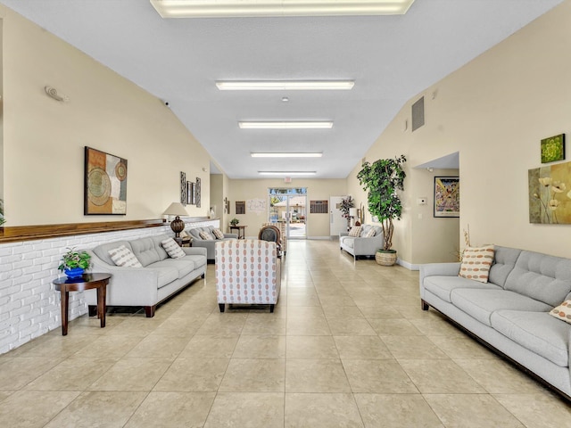 living area featuring light tile patterned floors, visible vents, and high vaulted ceiling