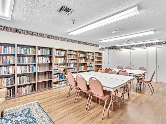 dining room with a textured ceiling, light wood-type flooring, and visible vents