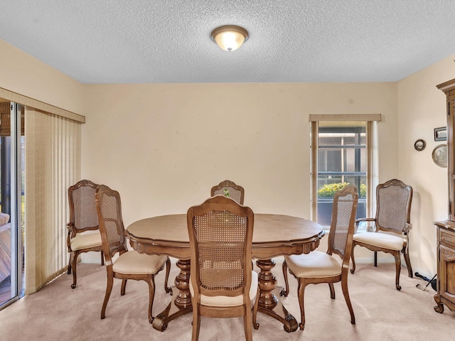 dining area featuring light colored carpet and a textured ceiling