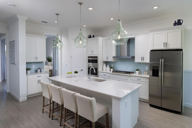 kitchen with a kitchen bar, light countertops, appliances with stainless steel finishes, a sink, and wall chimney exhaust hood