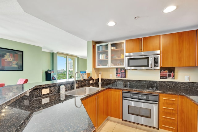 kitchen featuring appliances with stainless steel finishes, dark stone countertops, a sink, and glass insert cabinets