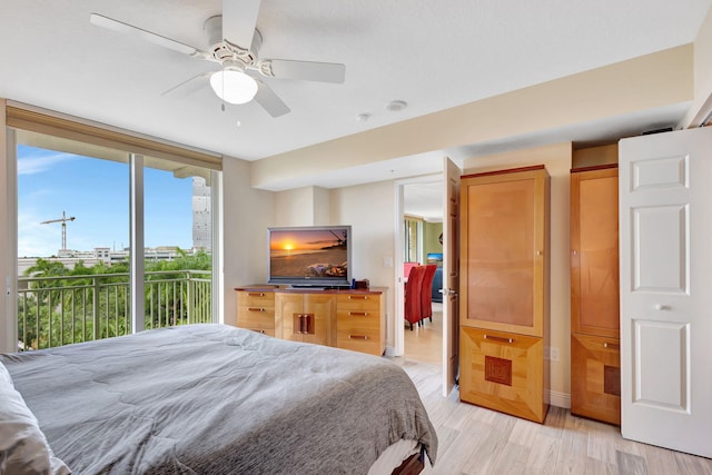 bedroom featuring access to outside, ceiling fan, light wood-style flooring, and expansive windows