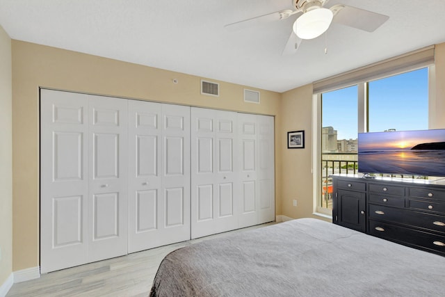 bedroom with light wood finished floors, ceiling fan, visible vents, and a closet